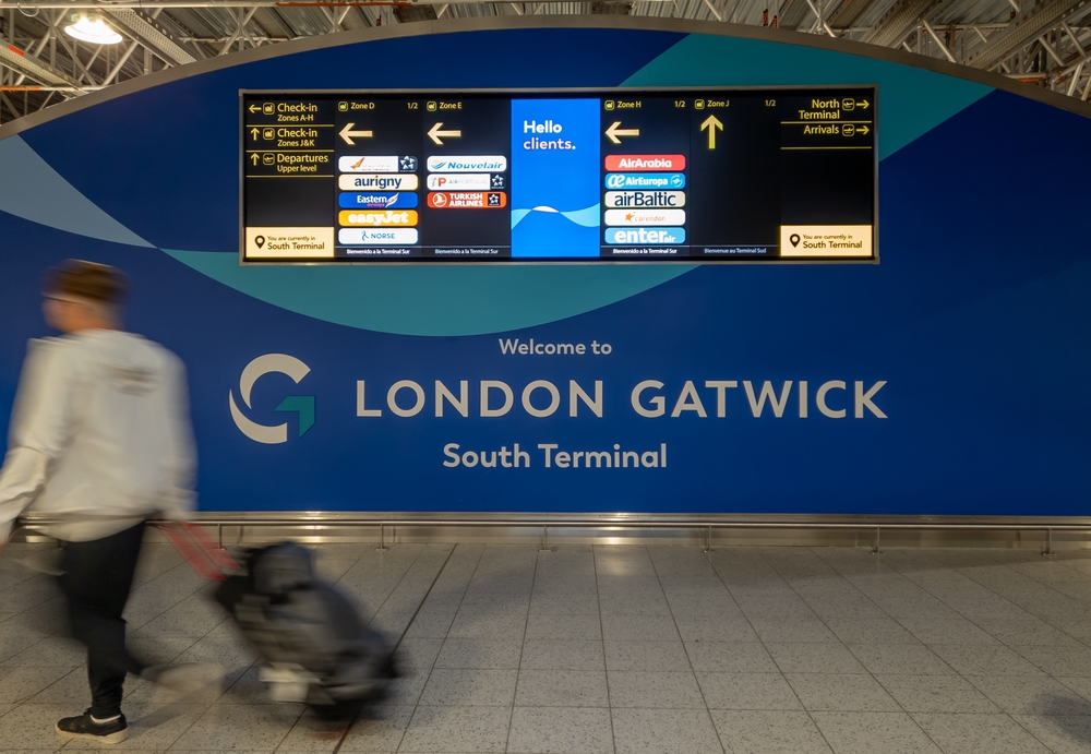 man walking into Gatwick airport with bag